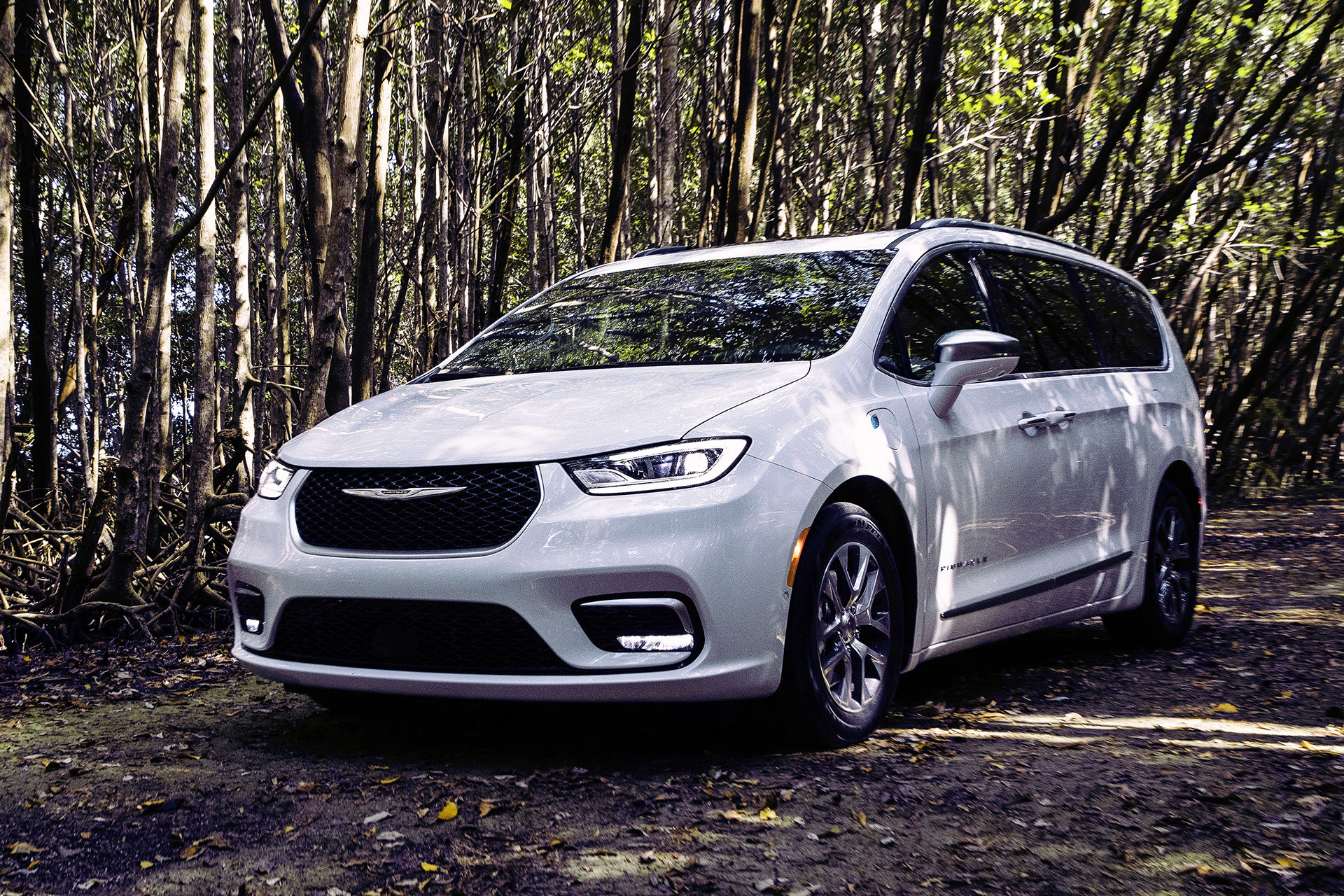 Front view of a white 2023 Chrysler parked on a forest path.