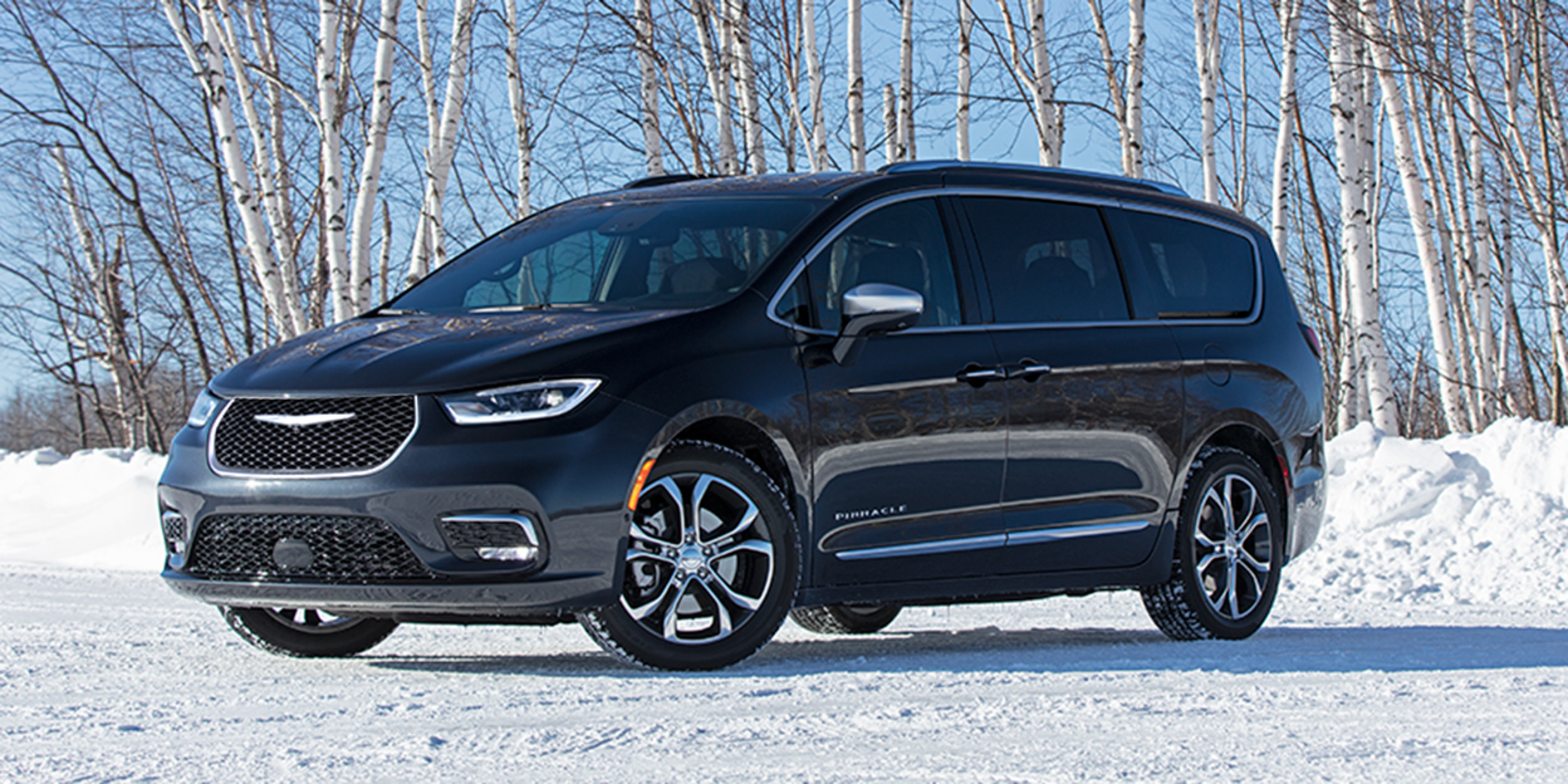 Pacifica Pinnacle AWD in Brilliant Black parked in a snowy field with trees behind.