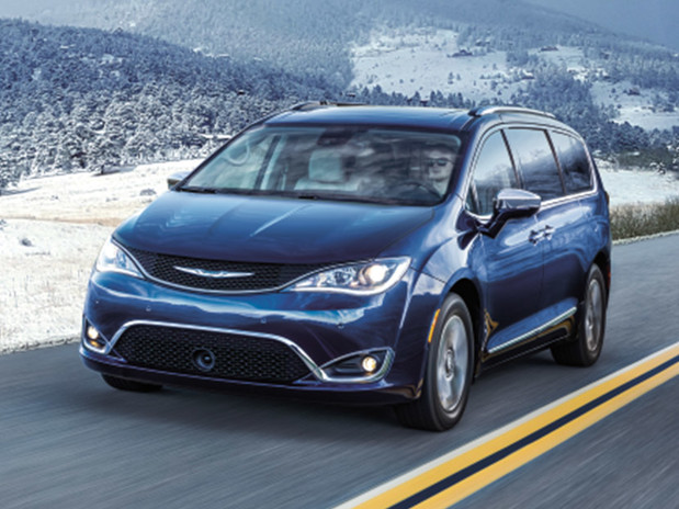 Chrysler Pacifica bleue roulant sur une route de campagne avec un paysage enneigé et des montagnes en arrière-plan.