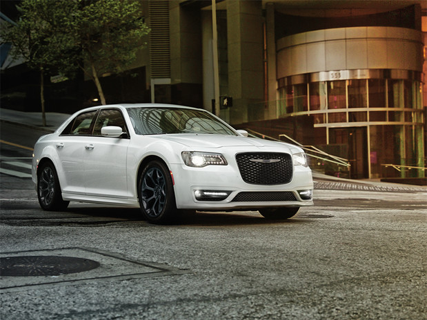 White Chrysler 300 parked on a street in front of a building.