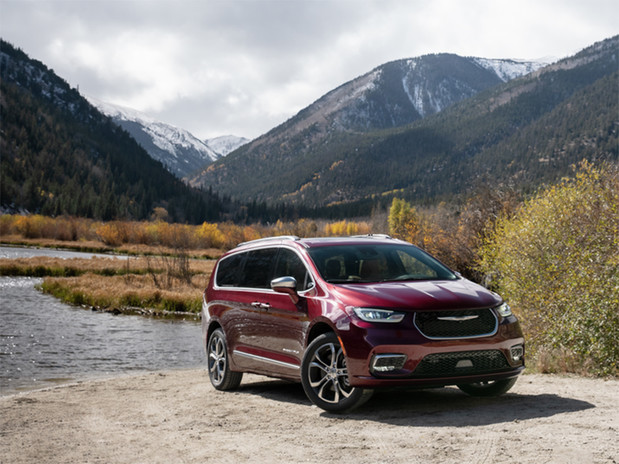 Red Chrysler Pacifica parked by a lake with mountains in the background.