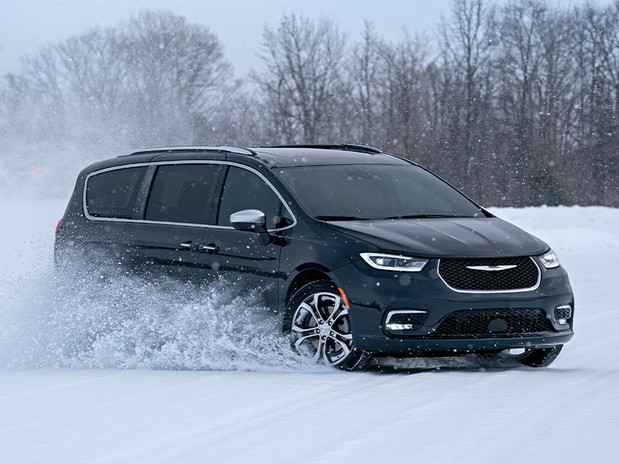 Pacifica Pinnacle AWD in Brilliant Black driving across a tree-lined snowy field.