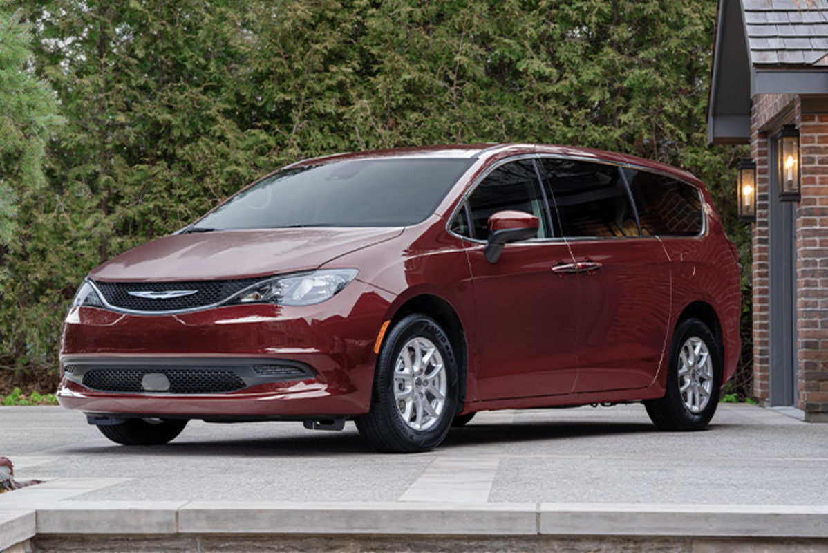 Recherchez votre offre Une Chrysler Grand Caravan rouge, garée dans l’allée d’une maison.