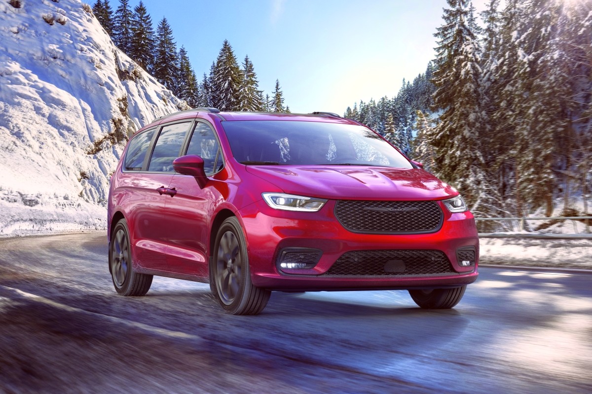 New 2021 Chrysler Pacifica in red driving down a road with snow covered mountains in the background
