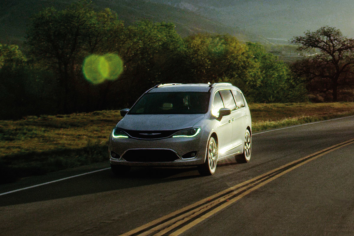 Une Chrysler Pacifica 2020 blanche roulant sur une route.