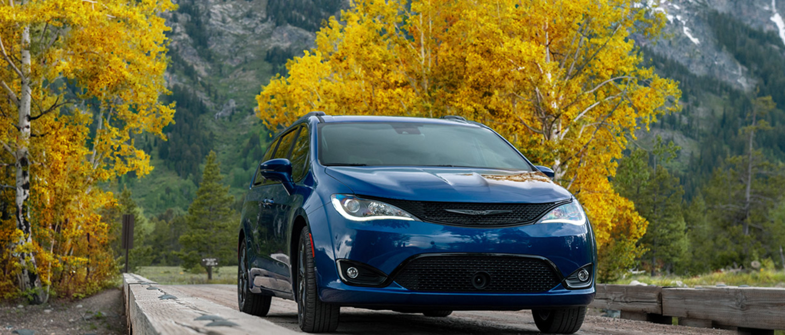 Une Chrysler Pacifica 2020 bleue roulant sur une route avec des montagnes en arrière-plan