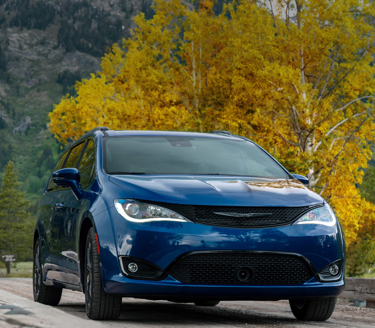 Une Chrysler Pacifica 2020 bleue roulant sur une route avec des montagnes en arrière-plan