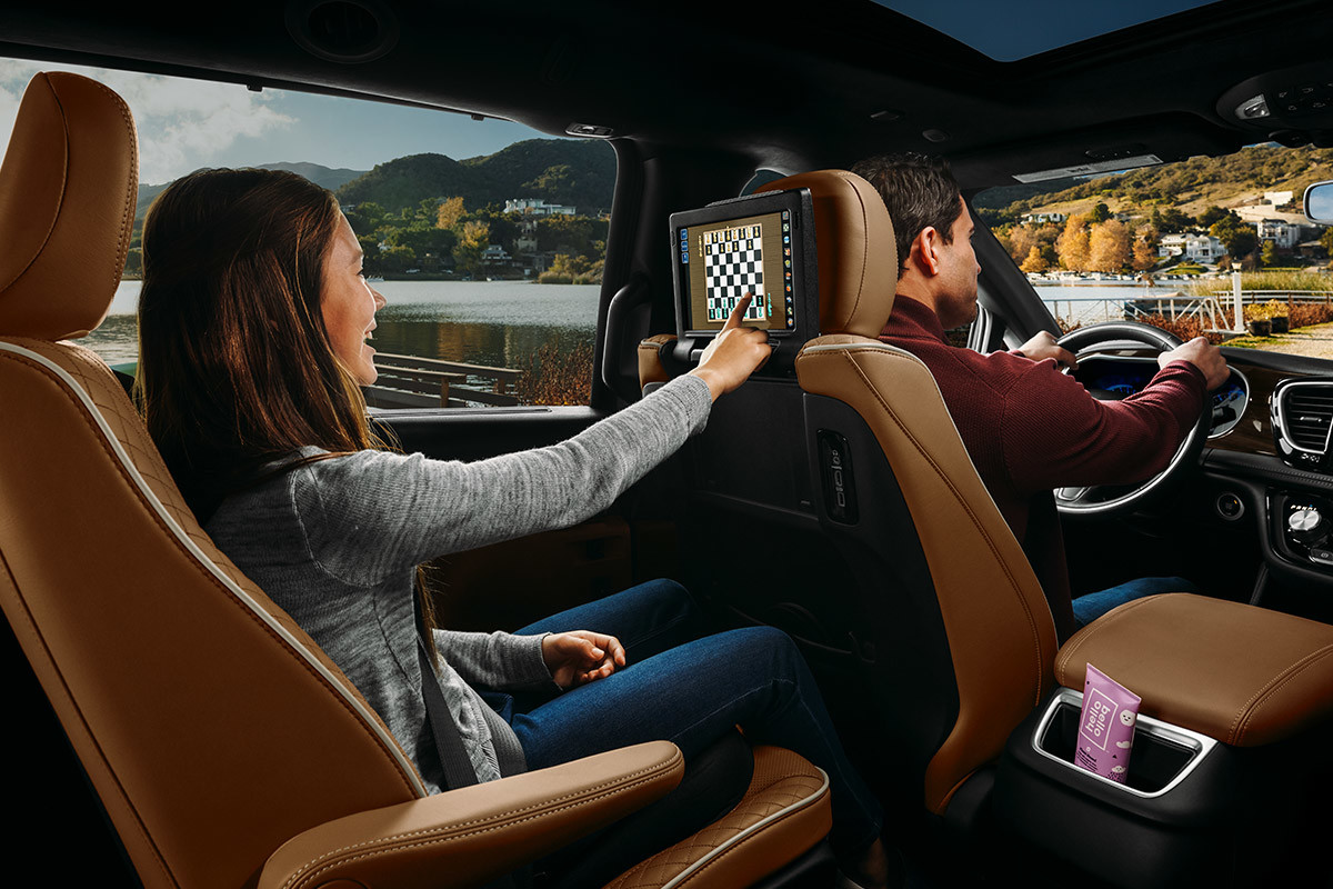 Gros plan d’une fille jouant aux échecs sur l’écran intégré au dossier d’un siège avant au moyen du système cinéma Uconnect livrable en option dans la Chrysler Pacifica Pinnacle 2021.