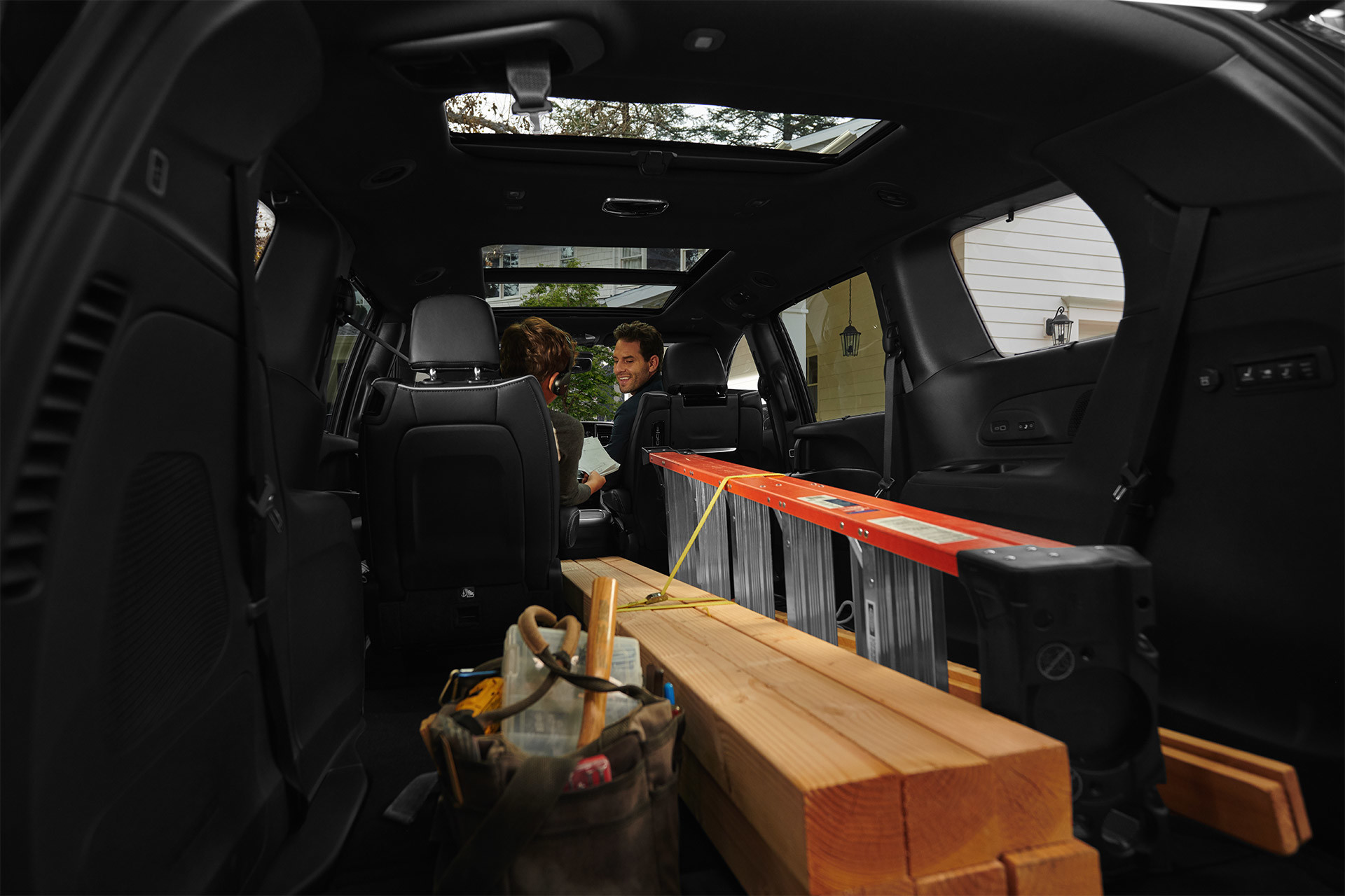 Vue intérieure arrière de l’espace utilitaire d’une Chrysler Pacifica avec les sièges des deuxième et troisième rangées retirés pour accueillir du bois, une échelle et du matériel.