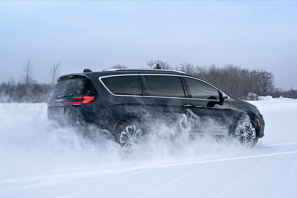 A black 2022 Chrysler Pacifica driving on snow.