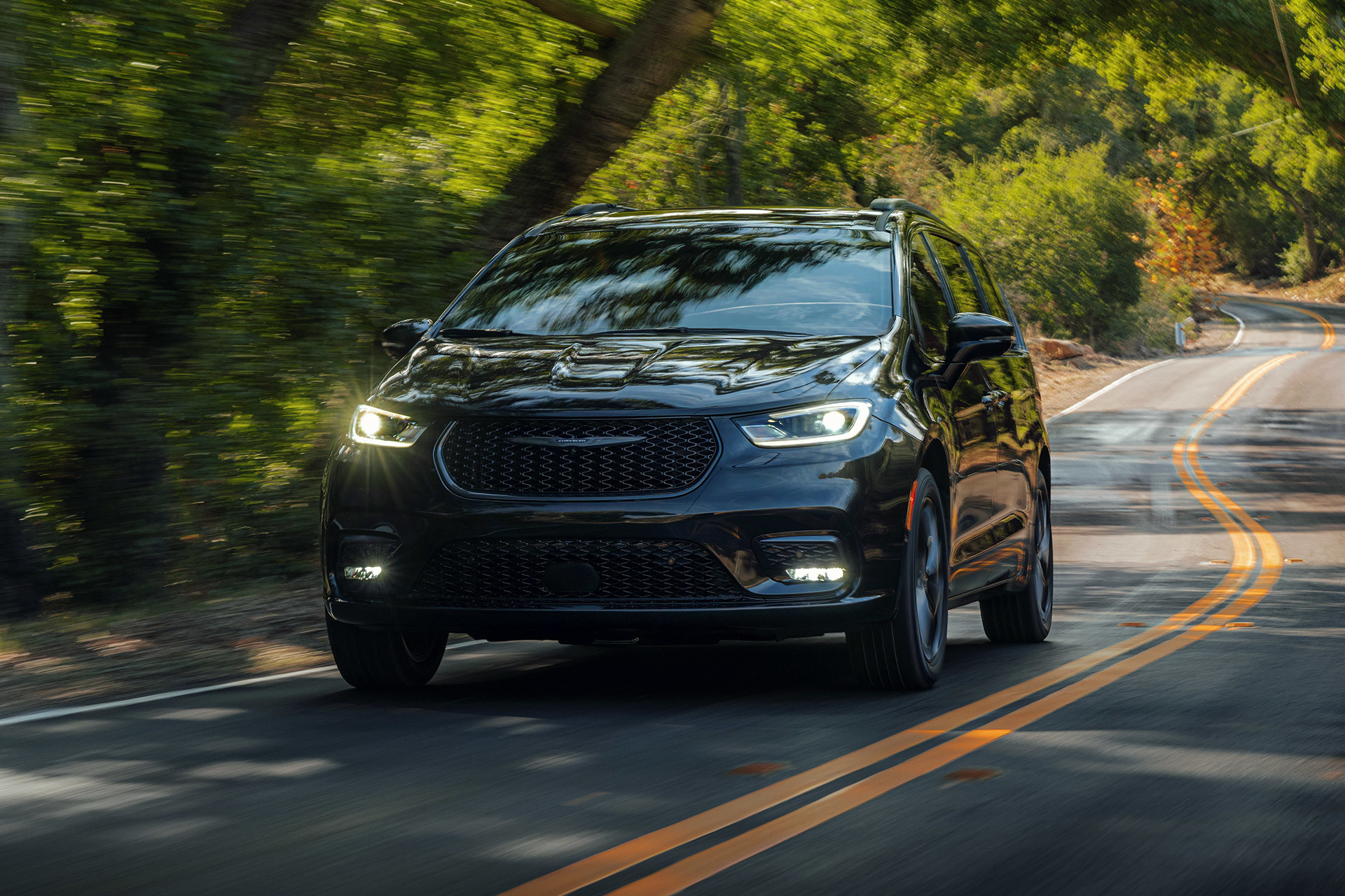 A grey 2022 Chrysler Pacifica driving down a forest road.
