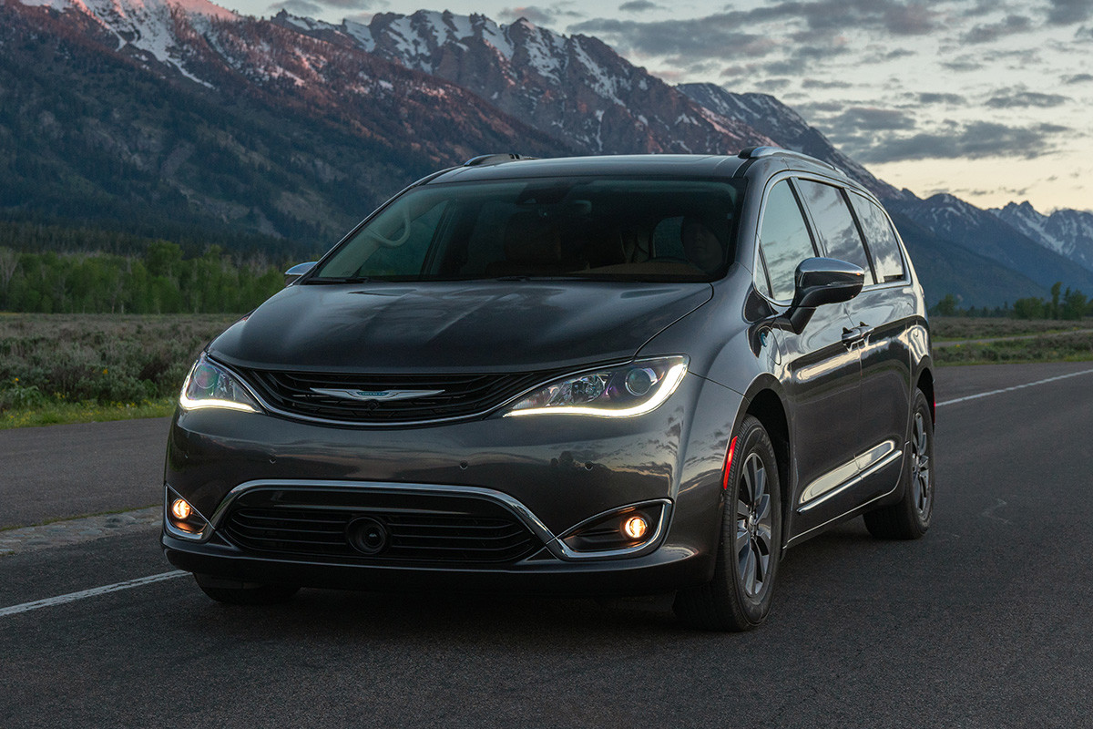 Une Chrysler Pacifica Hybrid 2019 grise roulant sur une autoroute avec des collines et des montagnes en arrière-plan.