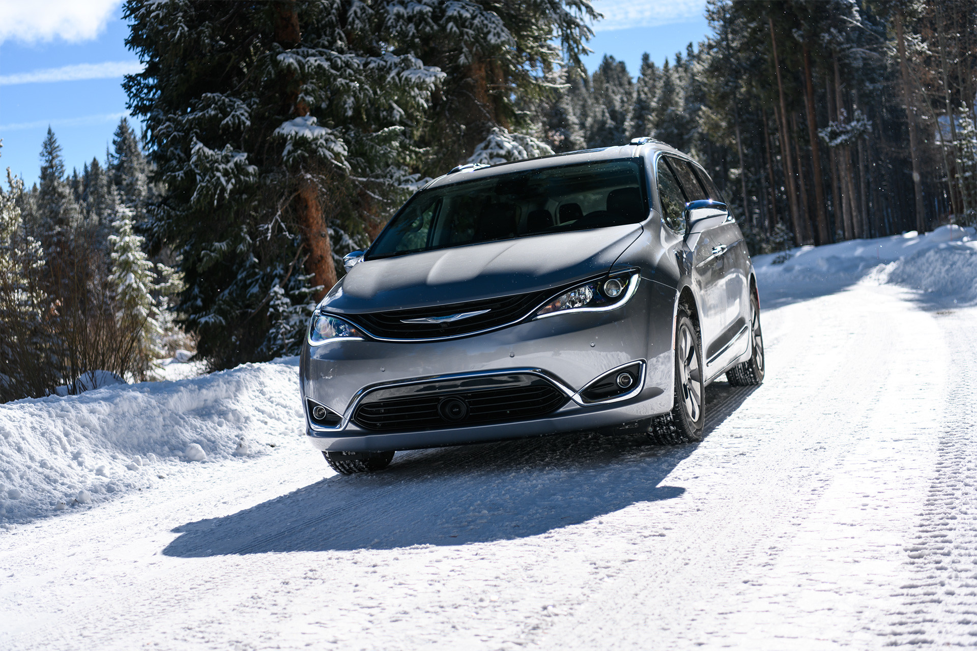 Front view of the silver 2019 Chrysler Pacifica Hybrid driving through a snowy forest