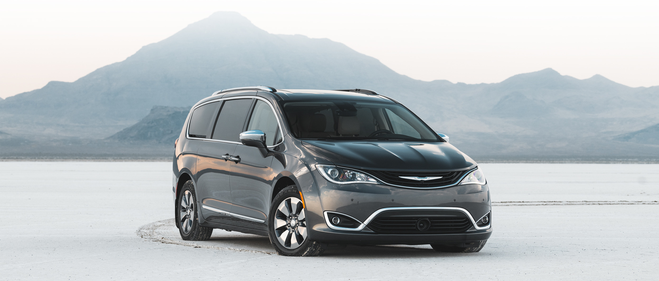 Vue de face de la Chrysler Pacifica Hybrid 2019, illustrée en gris, stationnée dans une clairière enneigée en montagne
