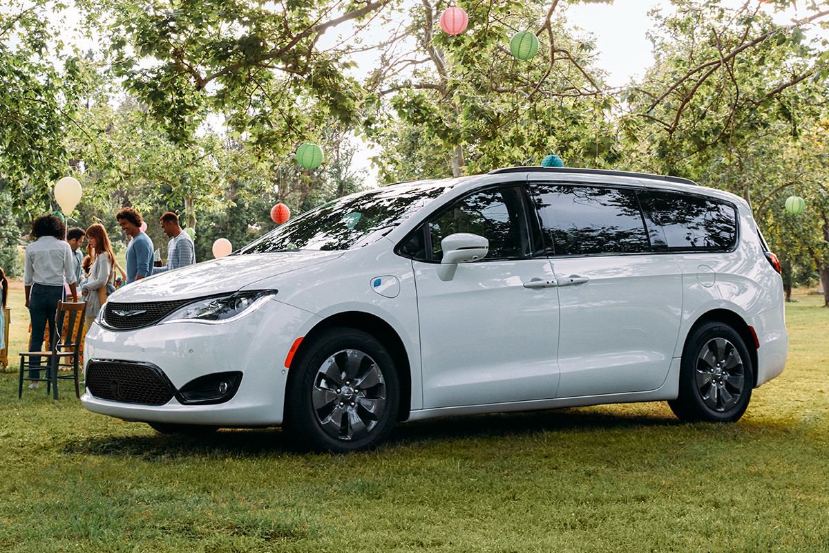 White Pacifica Hybrid, parked on the grass in front of an outdoor party at a park.