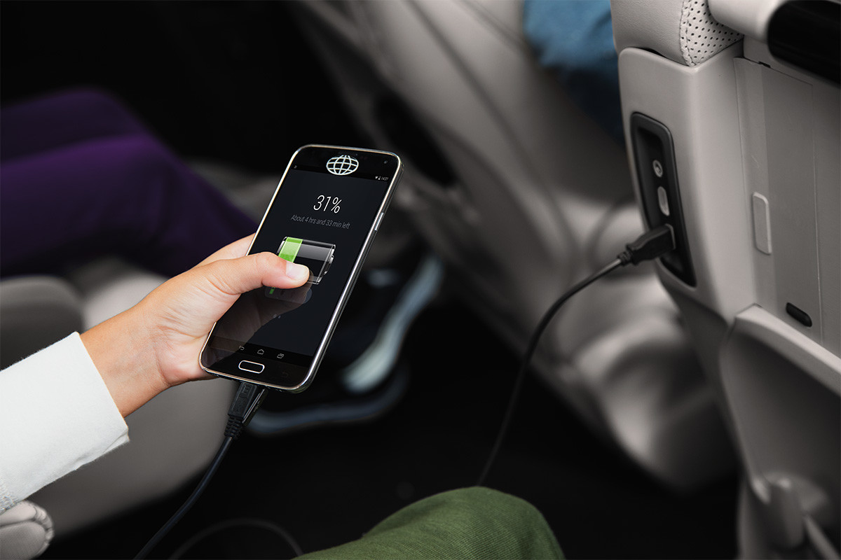 Personne tenant un téléphone intelligent dans le siège arrière de la Chrysler Pacifica Hybrid 2020 mettant en vedette les prises de courant aisément accessibles