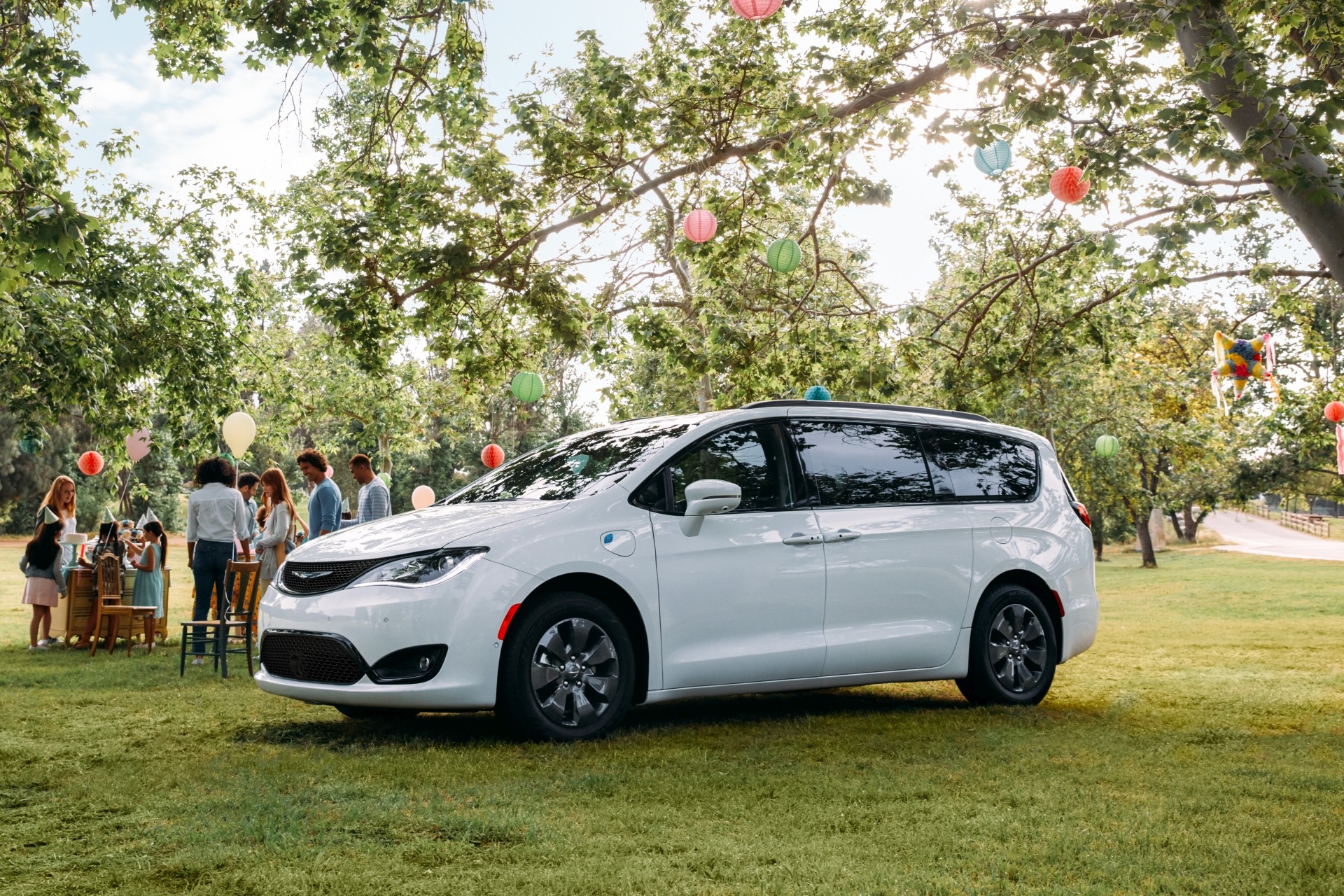 Chrysler Pacifica Hybrid 2020 blanche stationnée dans un parc, à côté d’un groupe de personnes
