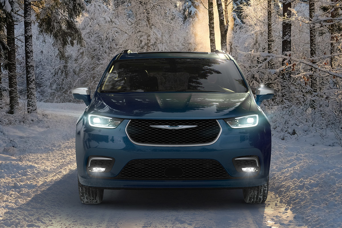 Front view of a 2021 Chrysler Pacifica Hybrid parked in the middle of a snowy forest