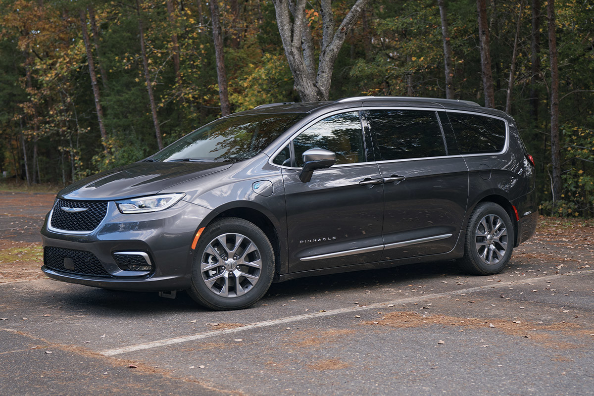 Vue de profil d’une Chrysler Pacifica Hybrid 2022 grise garée sur une route forestière