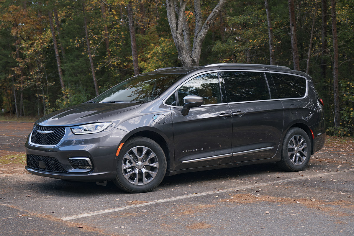 Vue de profil d’une Chrysler Pacifica Hybrid 2022 grise garée sur une route forestière