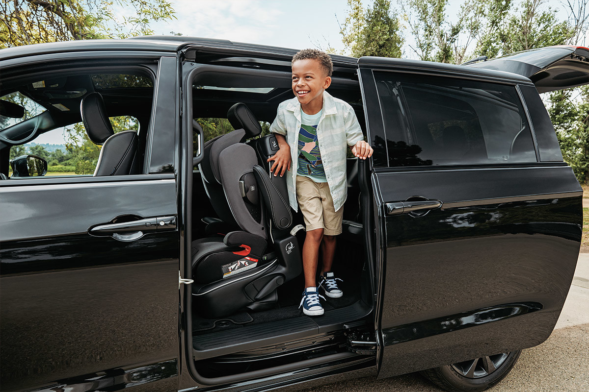 Un enfant debout devant la porte arrière d’une Chrysler Pacifica Hybrid 2022 noire