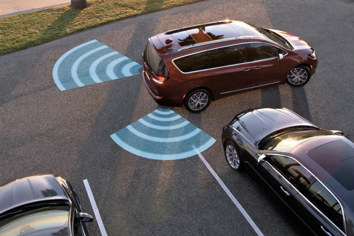 A red 2022 Chrysler Pacifica Hybrid demonstrating the standard safety features in a parking lot