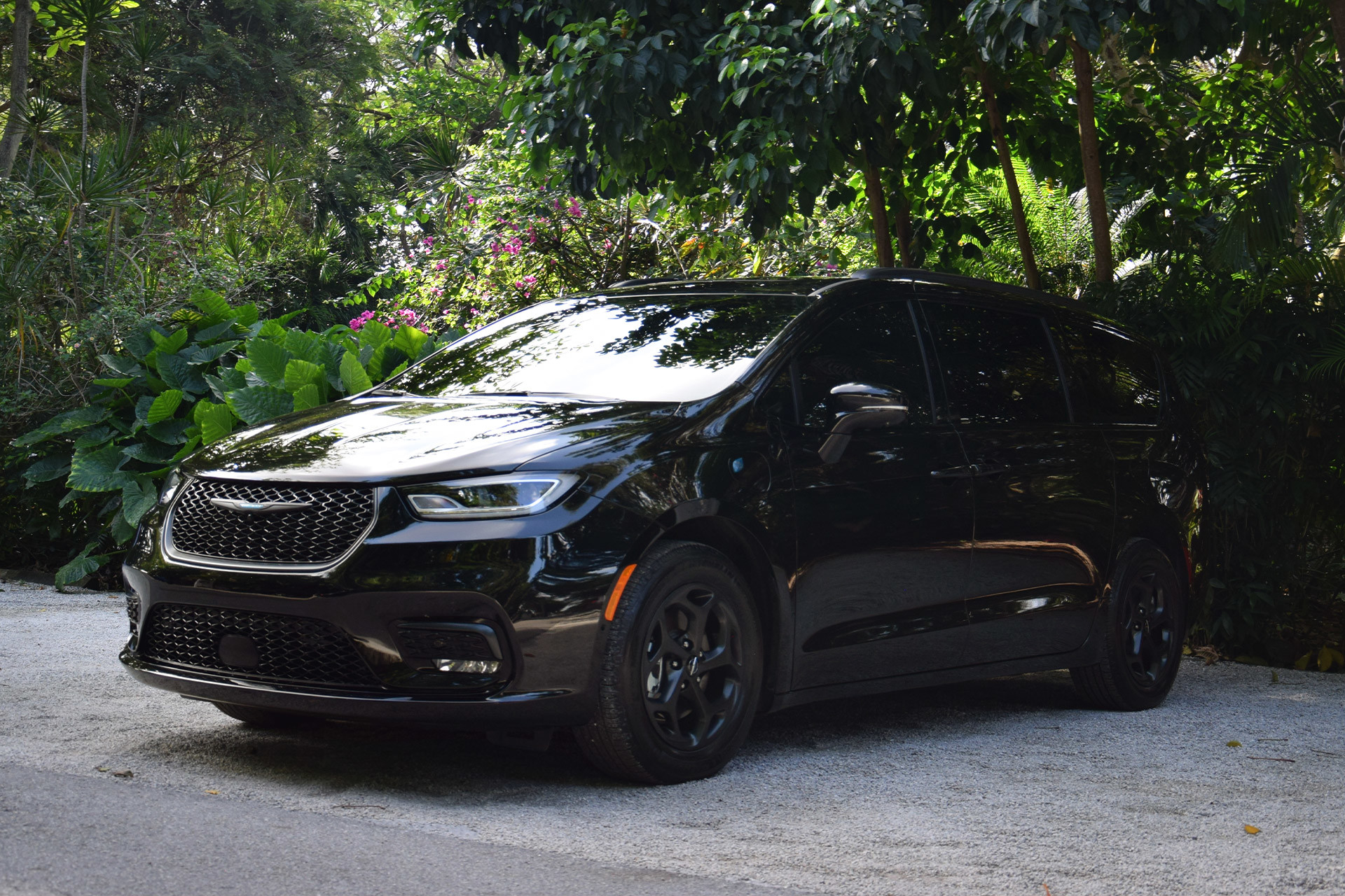 Une Chrysler Pacifica Hybrid noire garée sur une route forestière