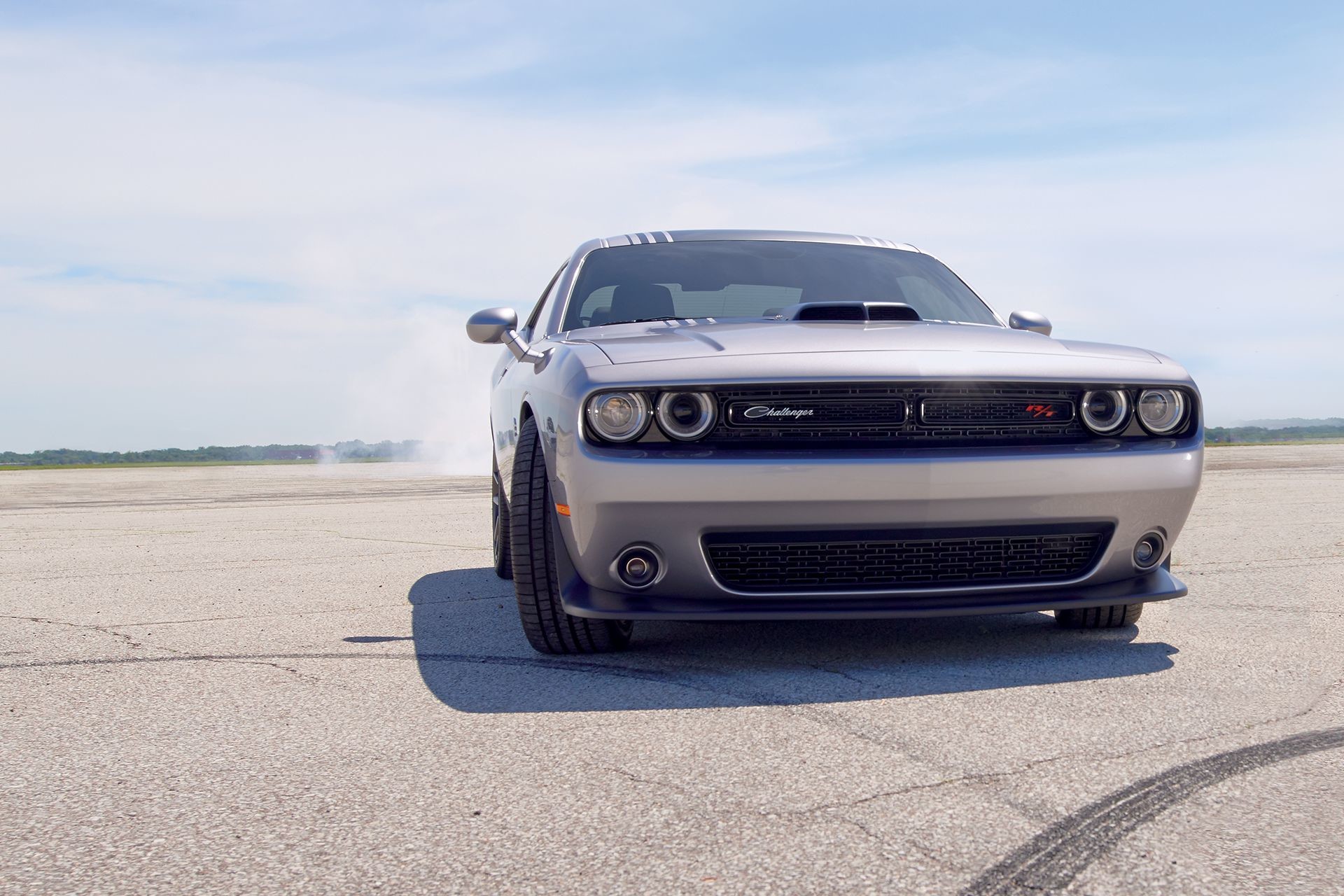 Une Dodge Challenger rouge stationnée près d’une forêt devant un pont en bois