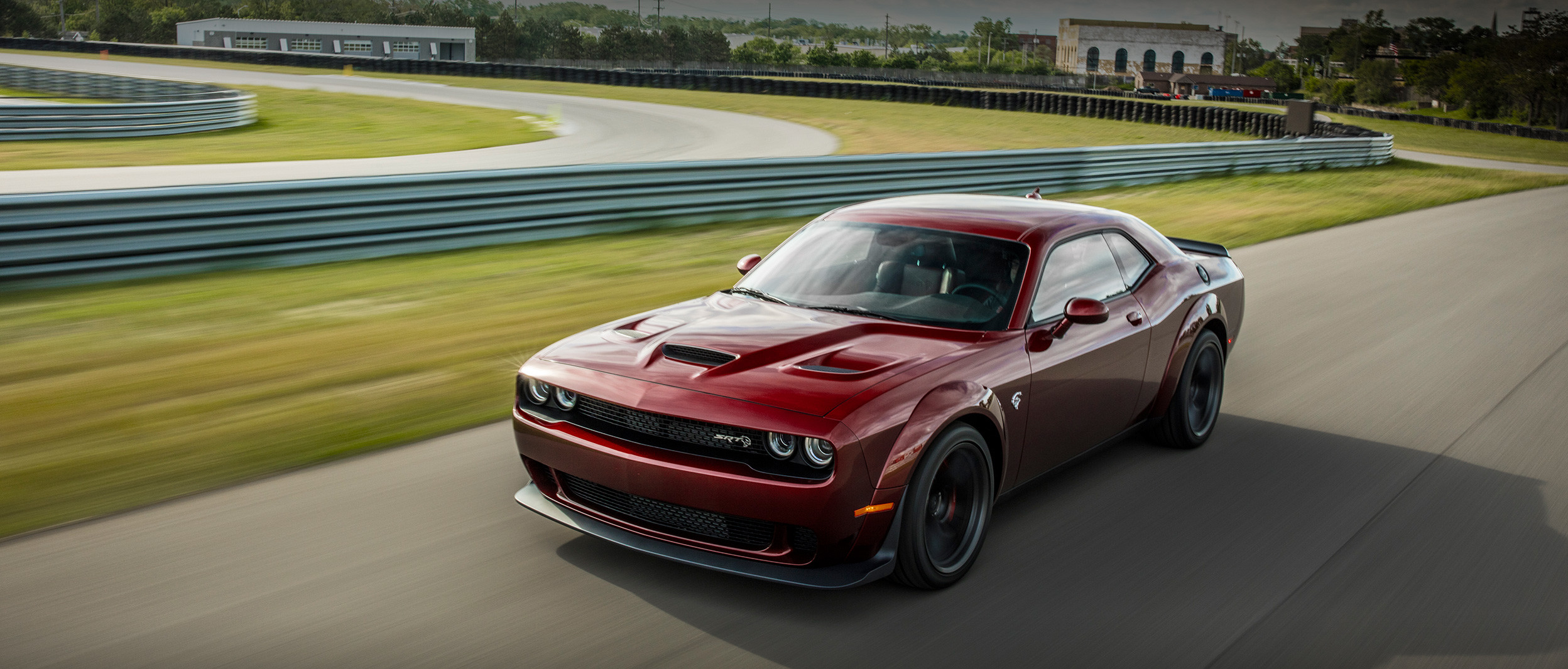 Une Dodge Challenger rouge foncé parcourt un circuit à vive allure