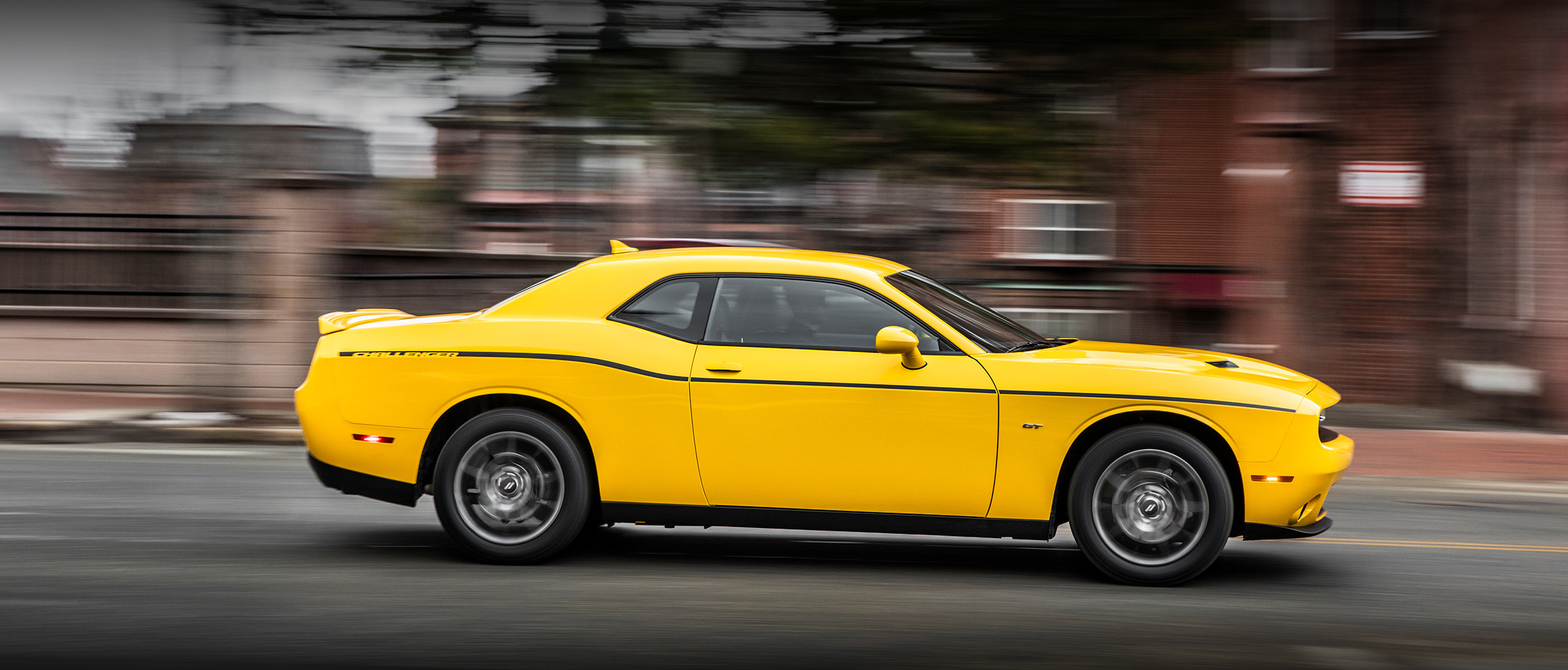 Une Dodge Challenger jaune roule dans une rue
