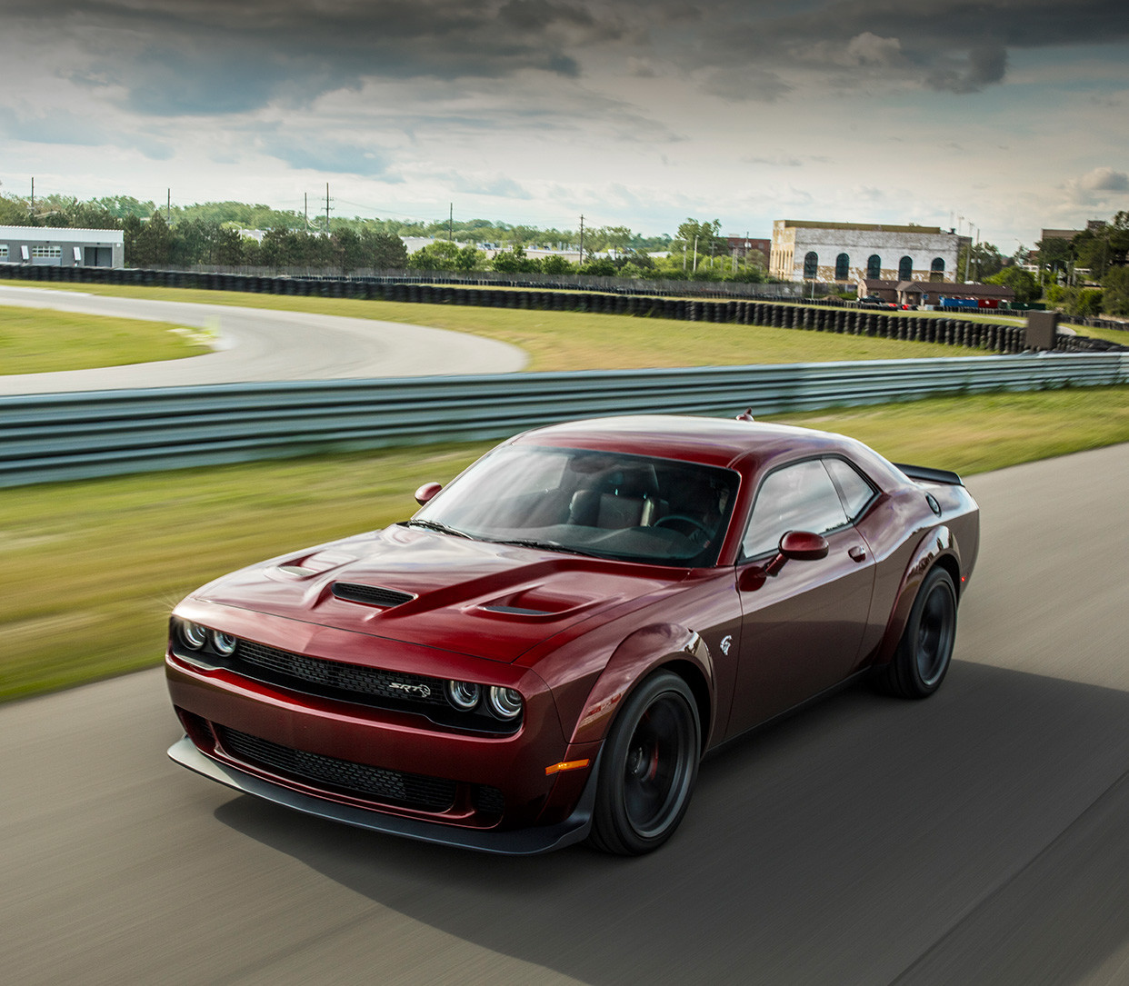 Une Dodge Challenger rouge foncé parcourt un circuit à vive allure