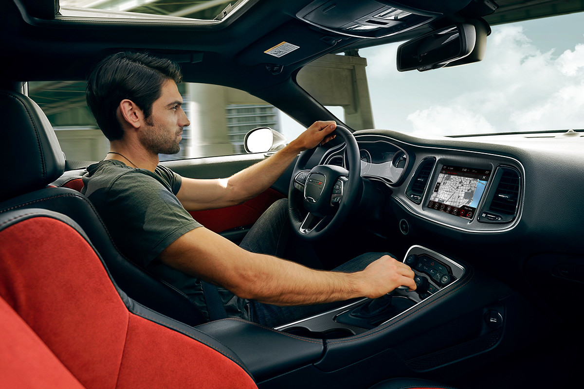 Man driving the 2020 Dodge Challenger while one hand is on the steering wheel and the other is on electronic shifter
