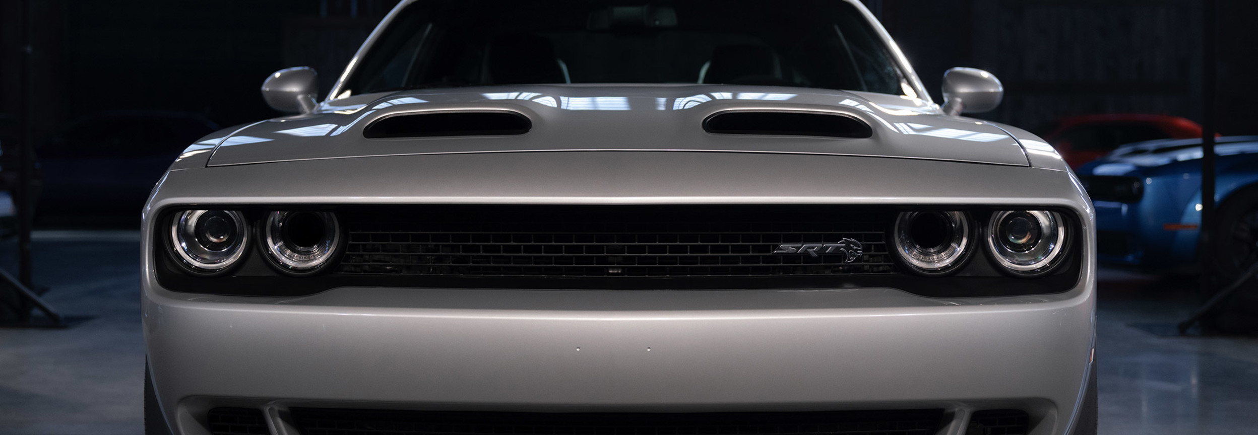 Front view of a silver 2021 Dodge Challenger parked inside a darke garage.