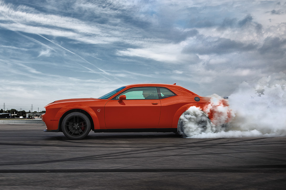 Side view of a 2021 Challenger burning rubber on a racetrack.