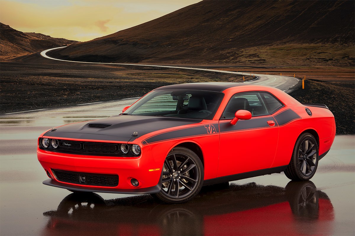 Dodge Challenger rouge avec l’ensemble allure extérieure T/A garée devant une route de montagne battue par les vents.