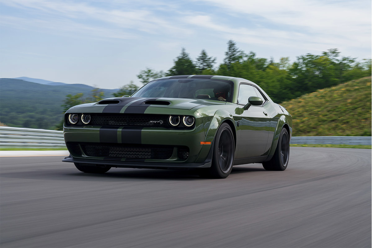 Une Dodge Challenger 2021 verte, dotée de l’ensemble allure spéciale Widebody, roulant sur une route sinueuse.