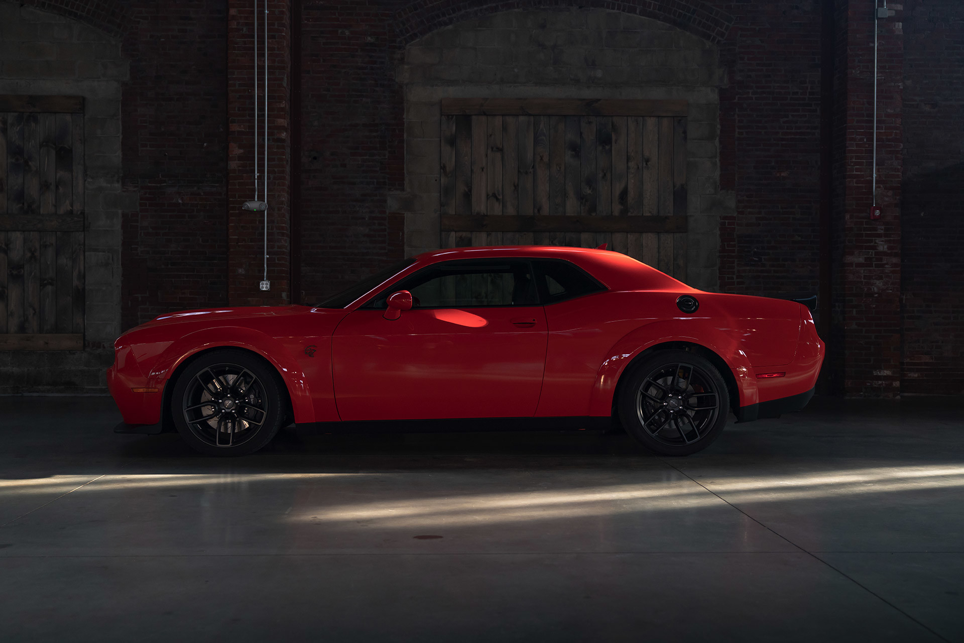 Dodge Challenger SRTMD Hellcat Redeye 2021 rouge stationnée dans une rue urbaine sombre.