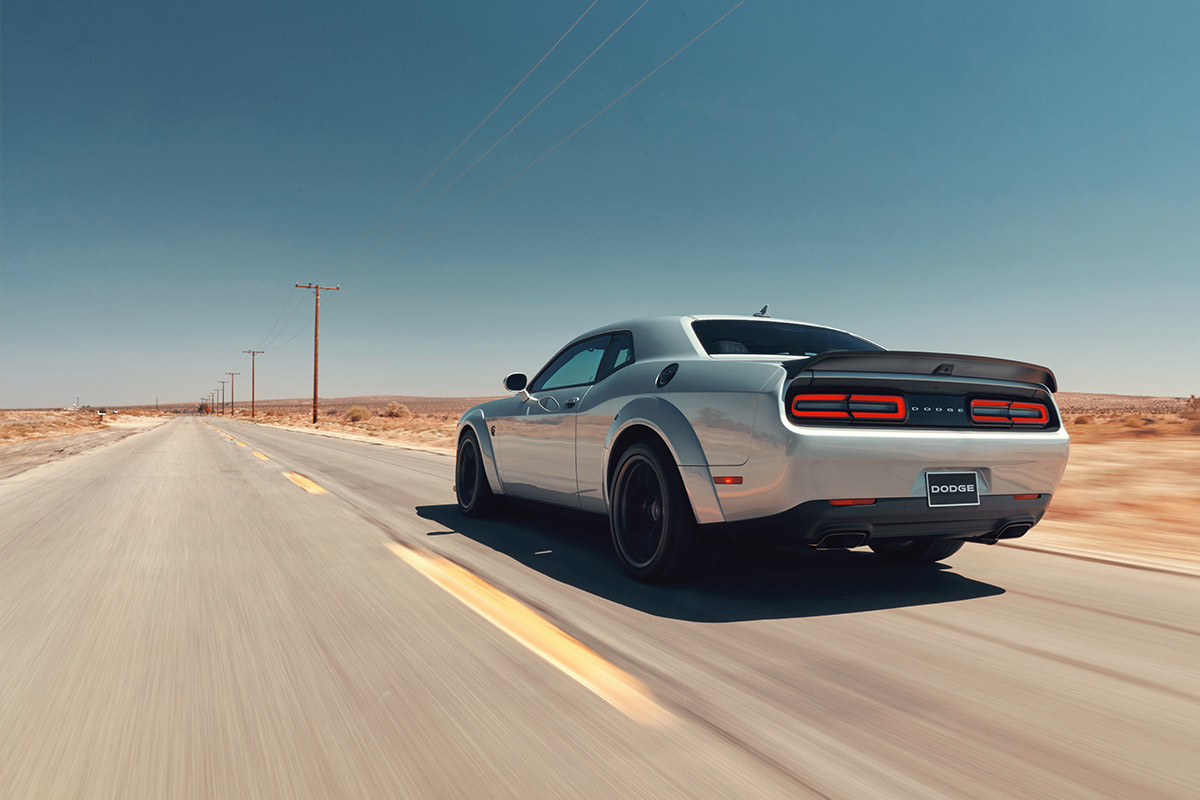 Une Dodge Challenger 2022 blanche roulant sur une autoroute dans le désert.