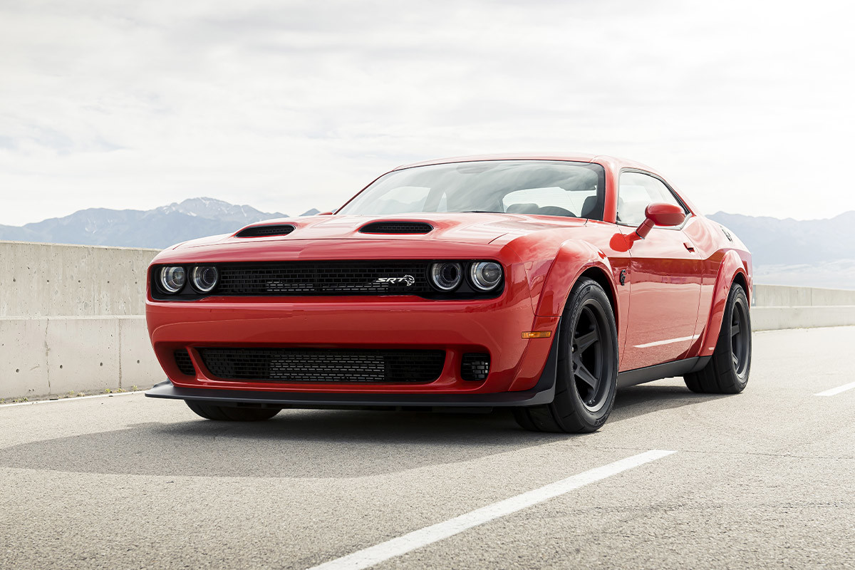 Une Dodge Challenger 2022 rouge garée sur une route pavée.