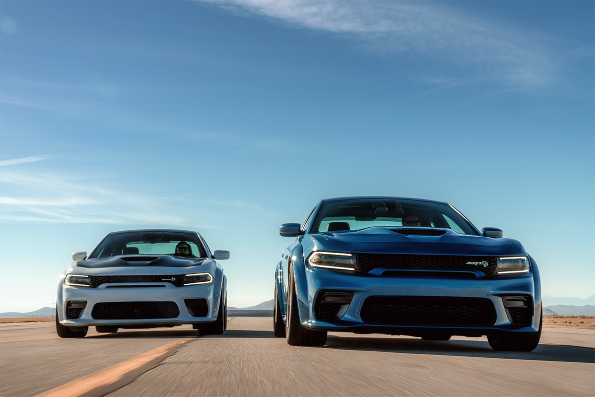 The blue 2020 Dodge Charger being driven next to the white 2020 Dodge Charger on a road