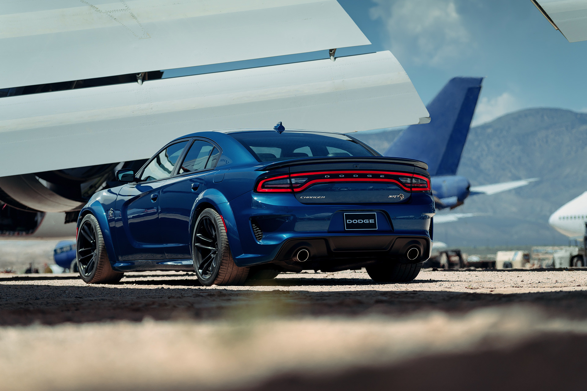 Rear view of the blue 2020 Dodge Charger parked in an airplane graveyard
