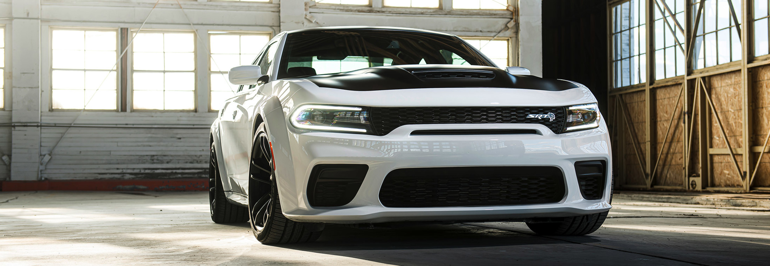 Front view of a white 2021 Dodge Charger parked in a warehouse garage