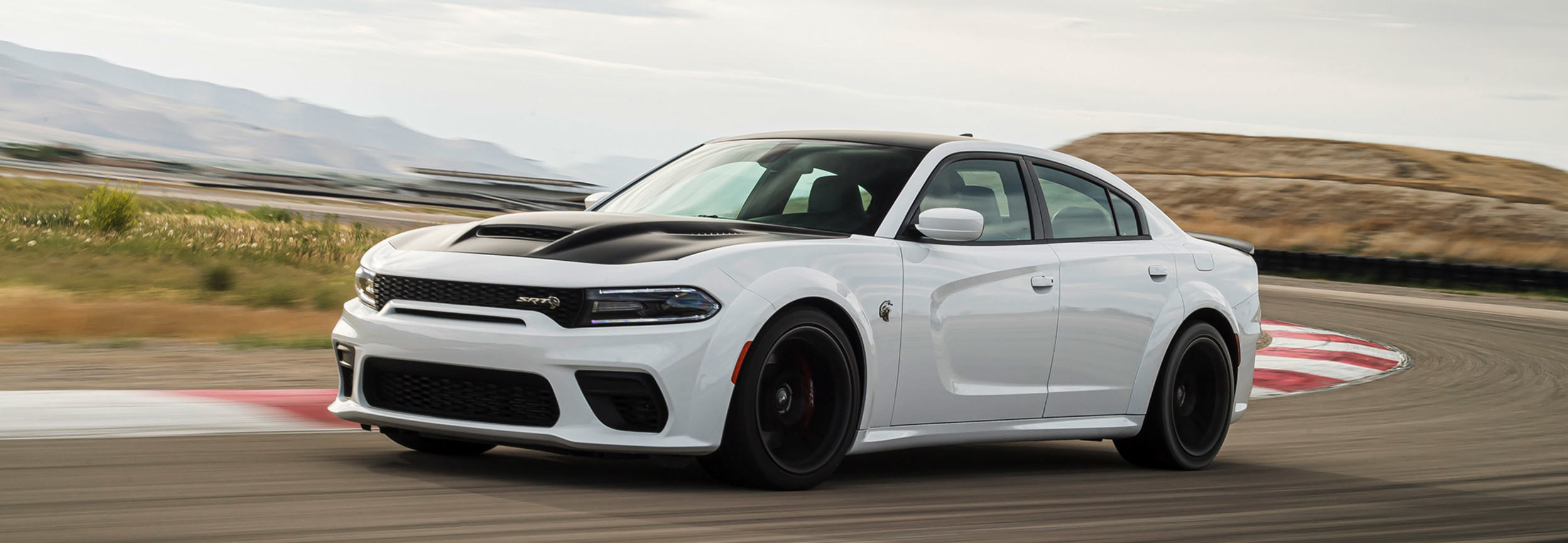 Une Dodge Charger 2021 blanche roulant à toute vitesse sur un circuit