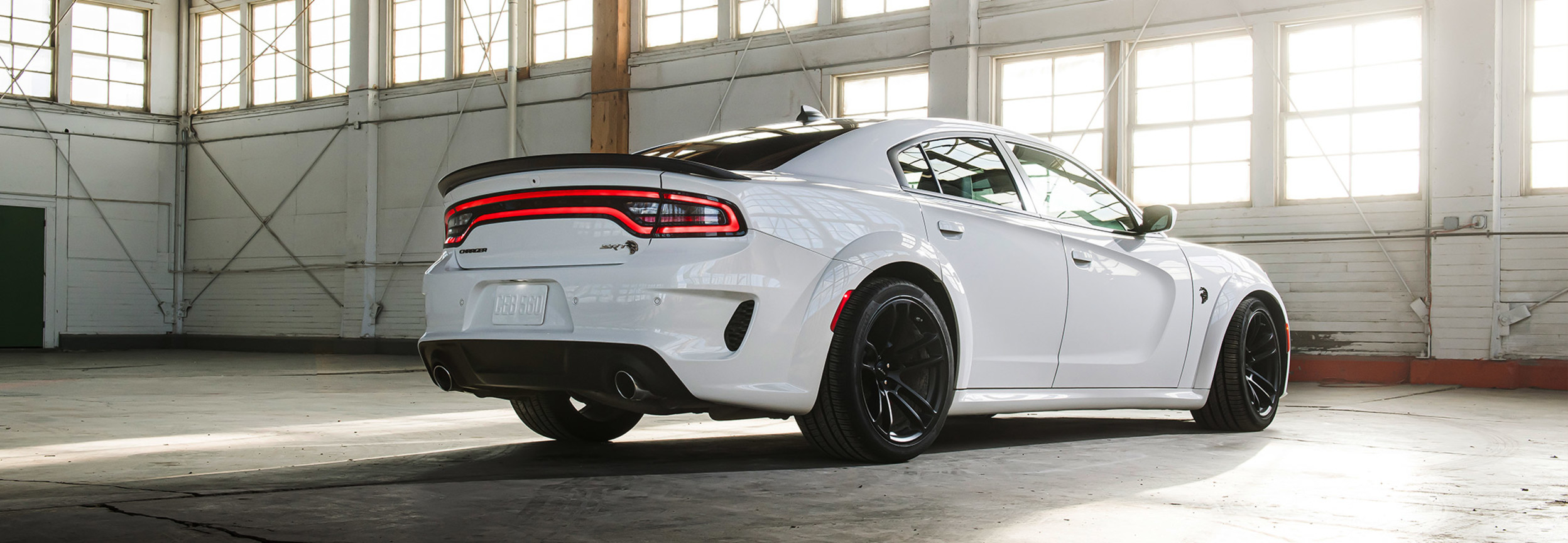 Rear view of a white 2021 Dodge Charger parked in a warehouse garage