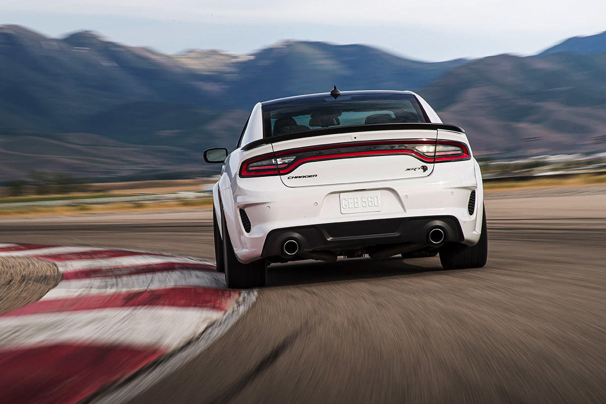 A rear view of a Whie Knuckle 2021 Dodge Charger Scat Pack thunders down a racetrack in the desert.