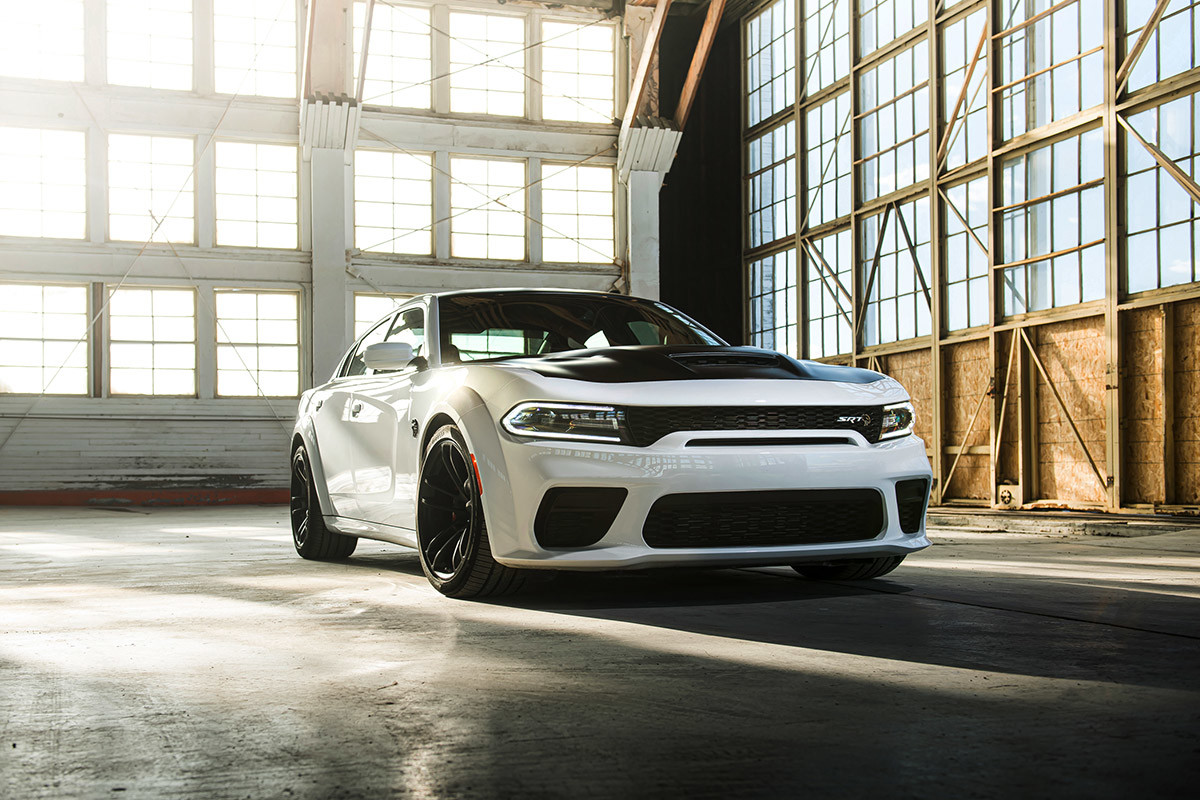 A white 2021 Dodge Charger parked in a warehouse garage with the sun peeking through the windows
