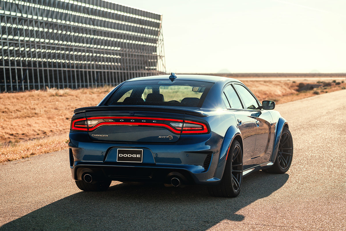 A rear view of an IndiGo Blue 2021 Dodge Charger parked on a racetrack in the desert.