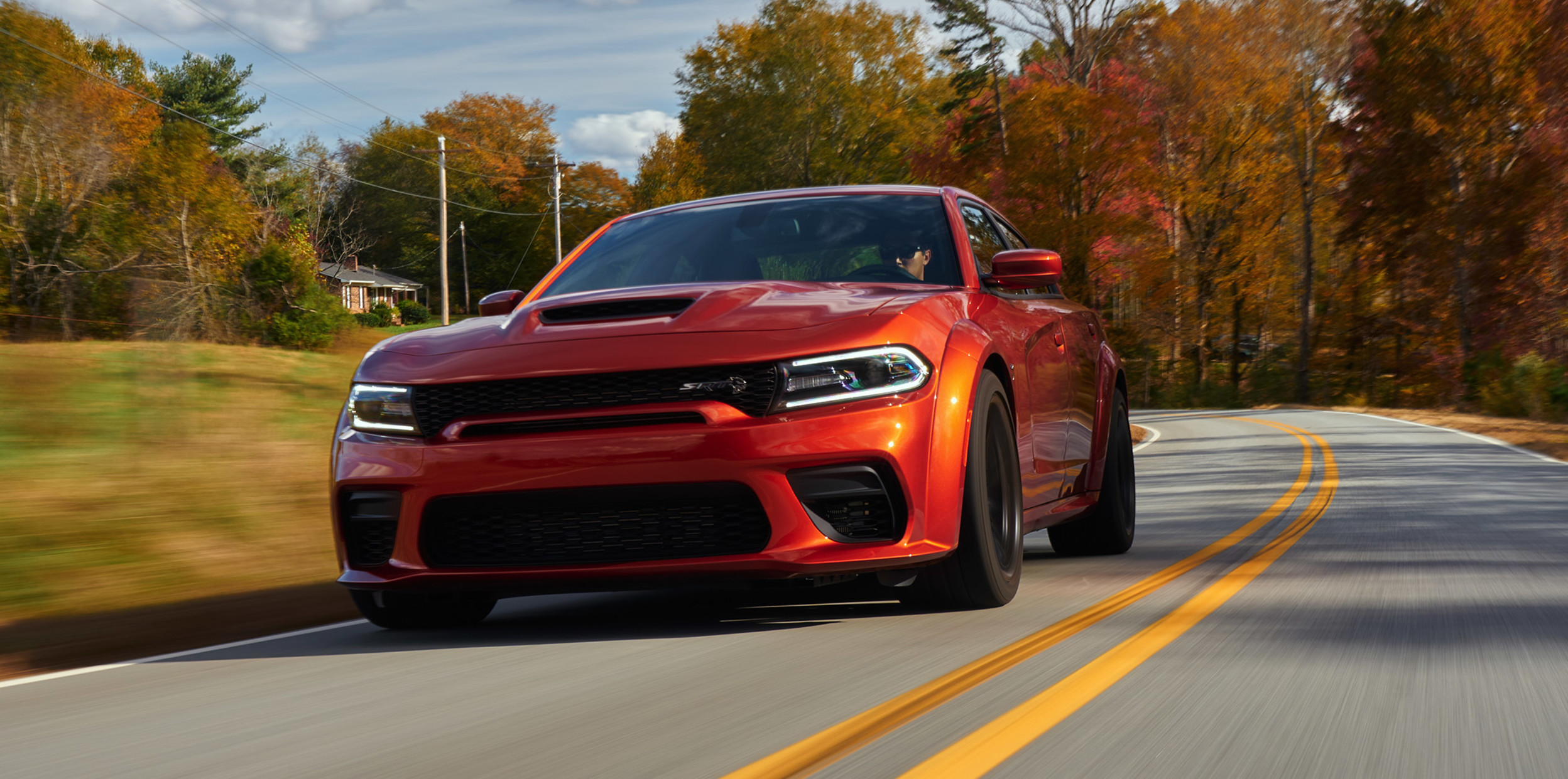 Dodge Charger 2022 rouge roulant sur une route de banlieue.