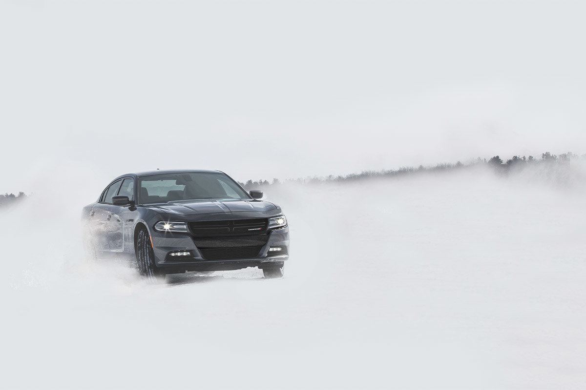 Une Dodge Charger 2022 noire roulant sur un chemin de neige hors route.