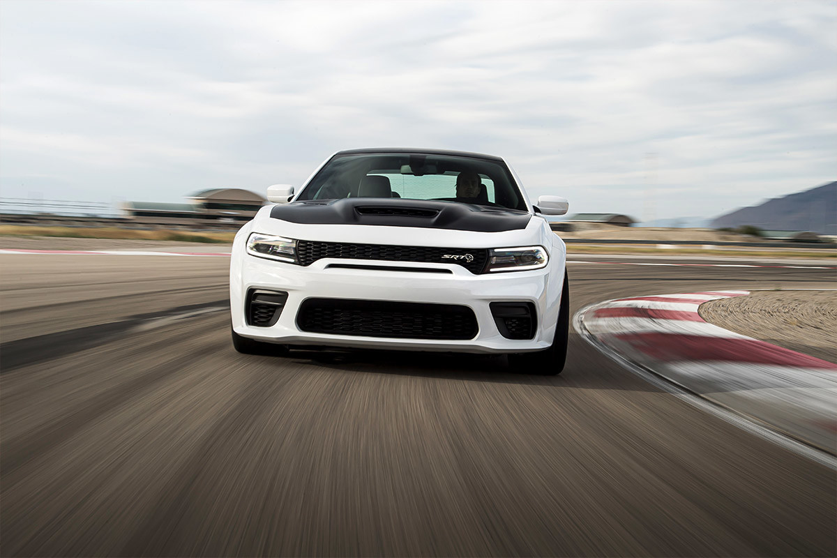 Dodge Charger 2022 blanche roulant à toute vitesse sur un circuit automobile.